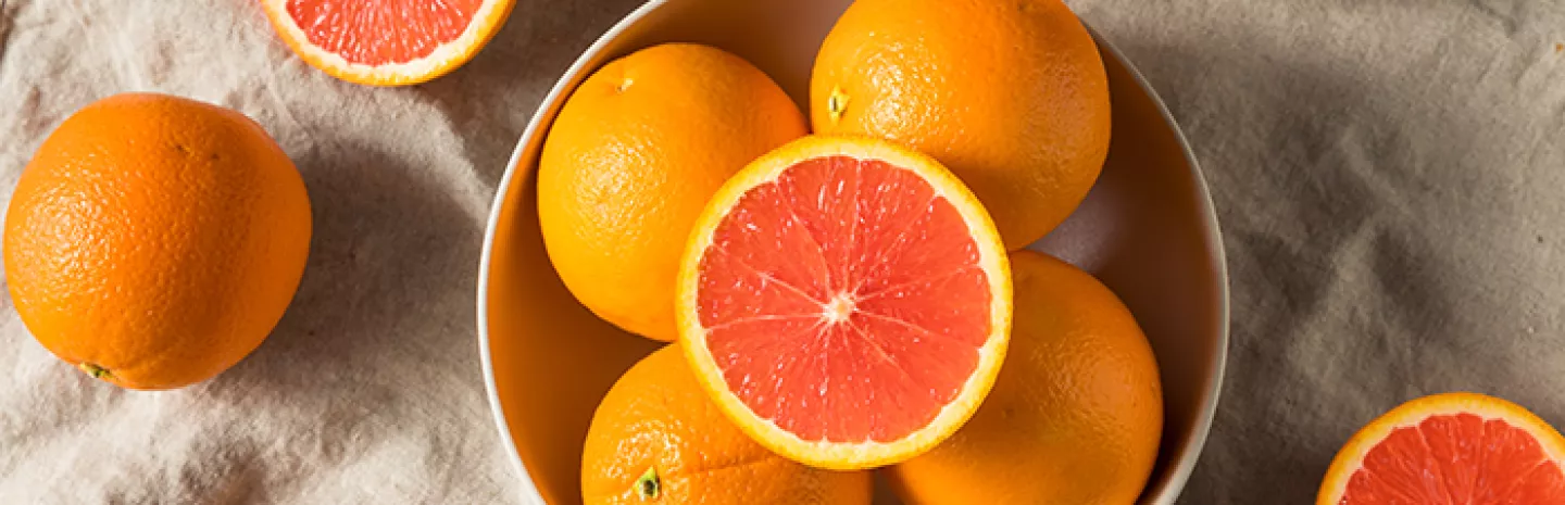 cara cara oranges in a bowl with some cut in half showing the pink inside