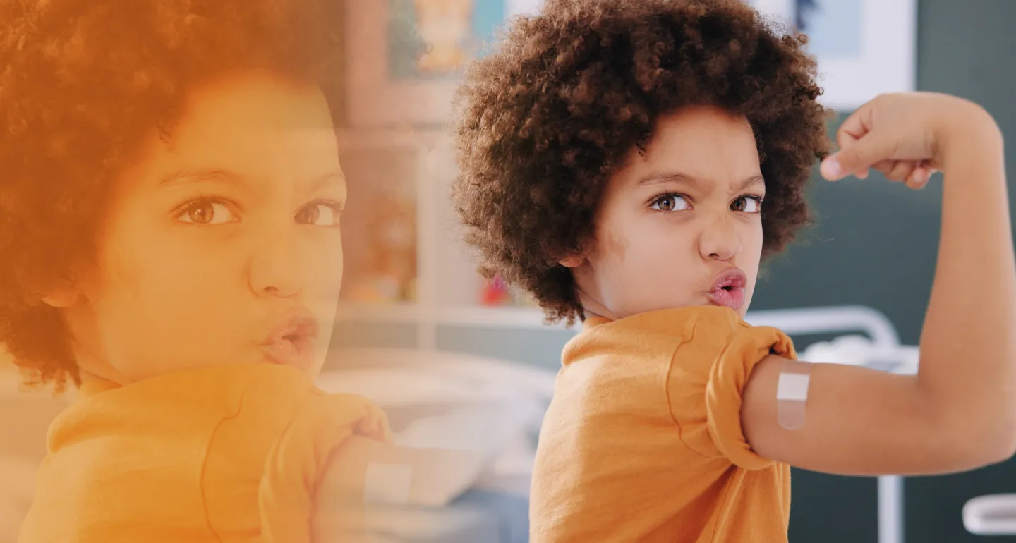 young child flexing muscles showing off a band-aid on their vaccine sight
