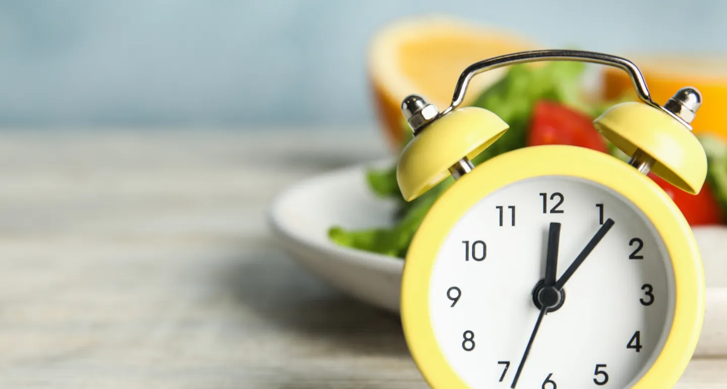 Yellow alarm clock sitting in front of a salad