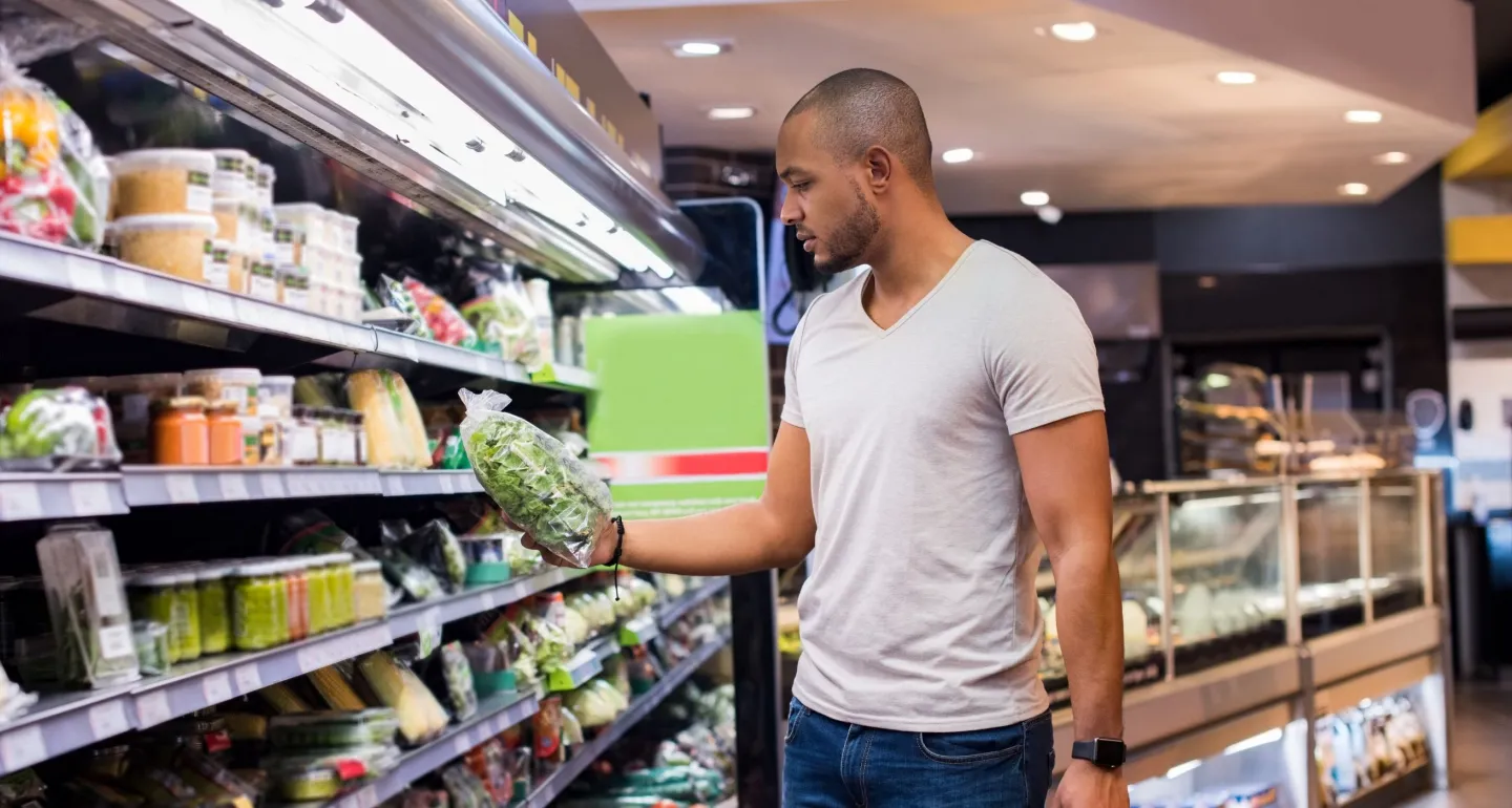 A man shops for bagged salad