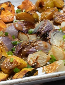 chopped winter vegetables sprinkled with sesame seeds and scallions roasted on baking sheet