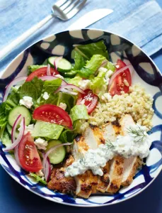 bowl on a blue background with greens and chicken