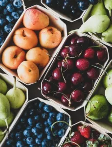 Seasonal produce - Flat-lay of ripe strawberries, cherries, grapes, blueberries, pears, apricots, figs in wooden eco-friendly boxes