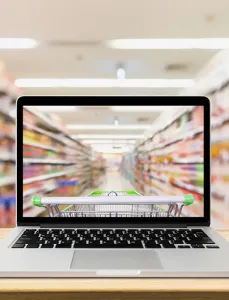 Laptop computer on wood table with supermarket aisle blurred background online shopping