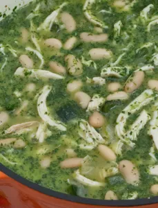 large orange ceramic pot filled with green chicken chili