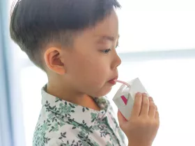 young child sipping from a juice box with straw