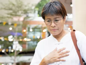 woman standing and holding her chest