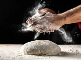 2 hands and raw dough covered in flour for baking