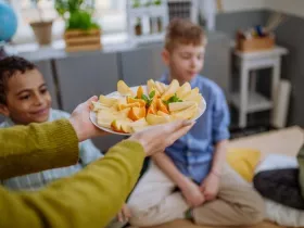 An instructor presents a healthy snack plate of fruit for students at an afterschool meeting