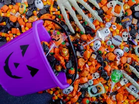 Halloween candy spilling out of purple pumpkin bucket