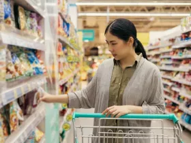 Asian woman shopping from the shelf to the shopping cart in supermarket