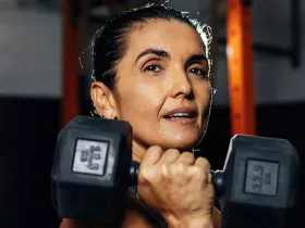 woman holding a dumbbell under her chin 