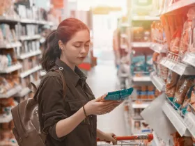 a woman reading a food package label in a grocery store