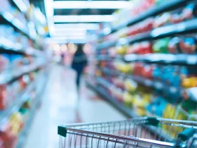 grocery cart in focus in the foreground with grocery store shelves out of focus in the background