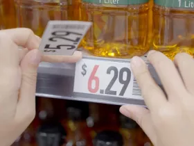 Closeup of grocery store worker increasing prices on cooking oil from $5.29 to $6.29. Rising food costs concept. 