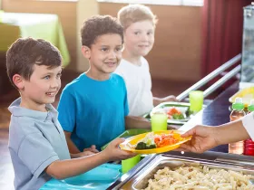 Woman serving food to schoolchildren