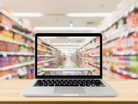 Laptop computer on wood table with supermarket aisle blurred background online shopping