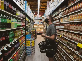 A man with a shopping basket eyeing the soda display in a supermarket