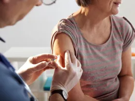 An older woman receives a vaccination shot in a doctor's office