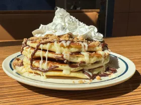 stack of 4 pancakes drizzled with chocolate icing, brown sugar and topped with whipped cream