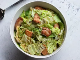 bowl filled with green cabbage and chicken stir fry on white counter