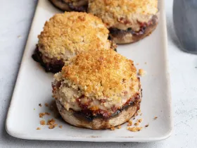white plate with 2 stuffed Portobello mushrooms topped with breadcrumbs