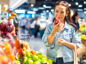 woman at grocery store holding a apple in the produce section