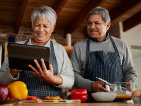 couple looking at an iPad and cooking in the kitchen