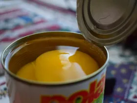 An open can of peaches in heavy syrup. 
