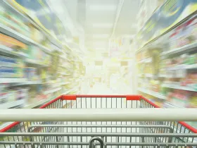 grocery cart in focus in the foreground with grocery store shelves out of focus in the background