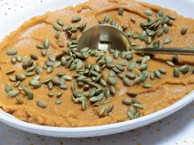 large bowl of sweet potato and butternut mash topped with pumpkin seeds