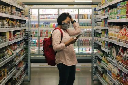 A woman in a grocery store peruses the snack aisle