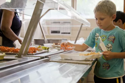A young boy takes food for his lunch tray from a buffet