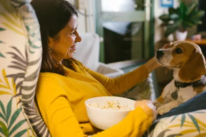 a woman eating popcorn while petting her dog