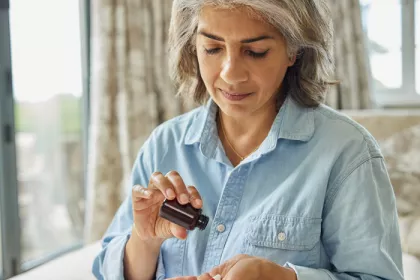 Woman pouring supplements into her hand from bottle
