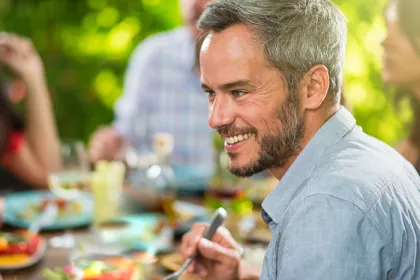 man smiling while eating with a group of people