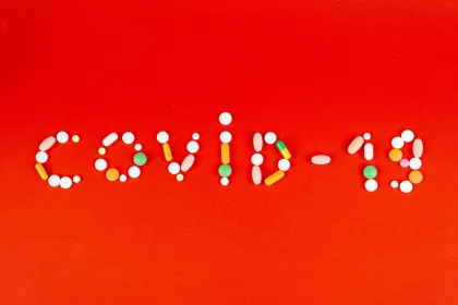 Various pills and capsules arranged to spell "Covid-19"