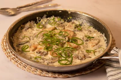 large pan filled with chicken, mushrooms, creamy sauce and topped with green scallion strips