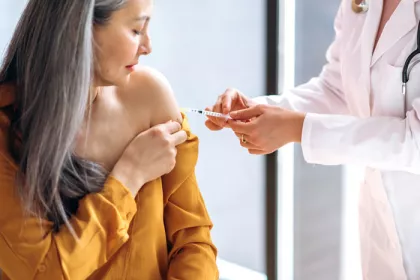 women in yellow top receiving a vaccine from the doctor