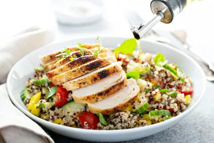 bowl of salad topped with chicken with olive oil drizzled on top