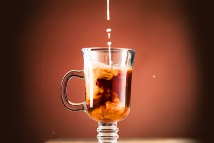 mug of coffee with creamer being poured in