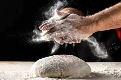 2 hands and raw dough covered in flour for baking
