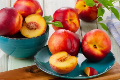 a blue bowl filled with nectarines next to a blue plate of nectarines