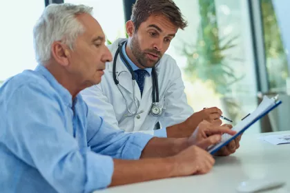 older man and doctor looking and pointing at a tablet