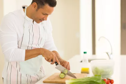 man chopping vegetables in bright kitchen