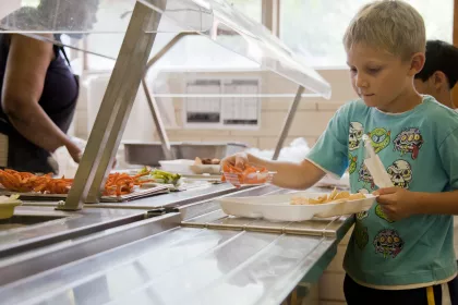 A boy in the school cafeteria adding foods his lunch tray