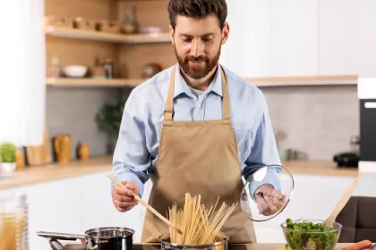 a man cooking pasta in a kitchen