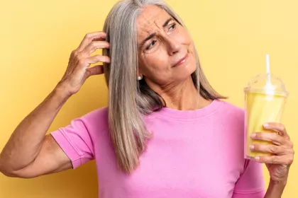 Older woman scratching her head and holding a yellow shake
