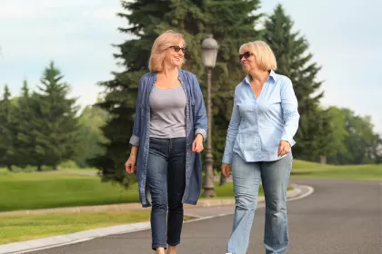 two women walking on a tree lined street
