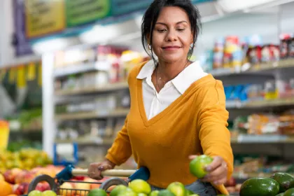 woman picking up a green apple in a grocery store